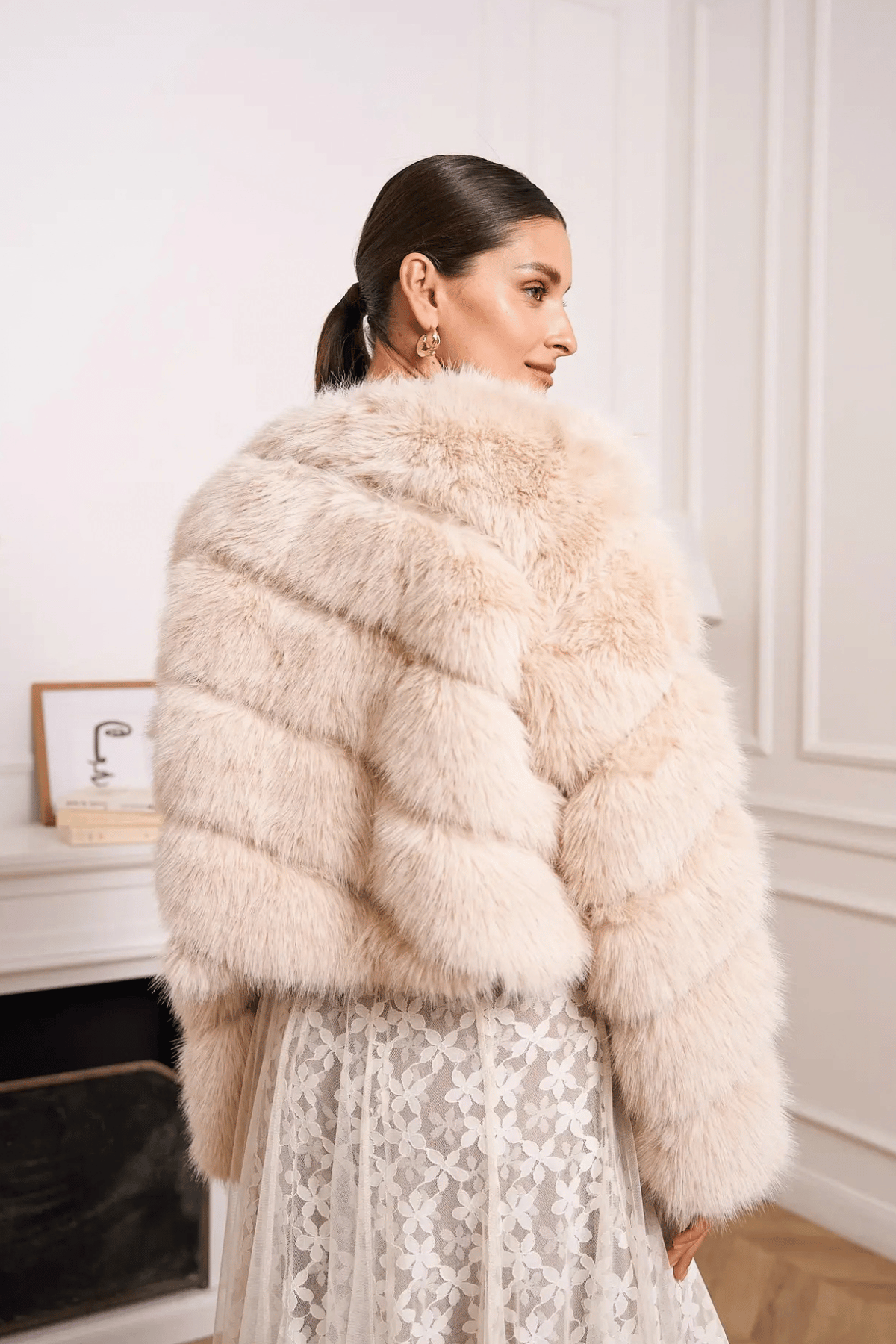 Paula beige faux fur jacket with horizontal banding, styled over an ivory lace skirt